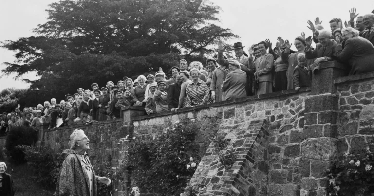 Clementine Churchill (1885-1977) saluda con la mano a los visitantes que la saludan desde lo alto de un jardín amurallado en Chartwell, Kent, el 11 de junio de 1959. (Foto de Evening Standard/Hulton Archive/Getty Images)